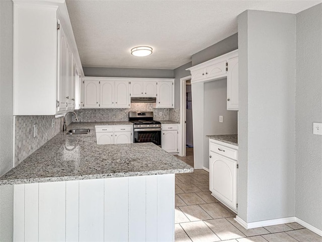 kitchen featuring white cabinets, sink, light stone countertops, stainless steel range oven, and kitchen peninsula