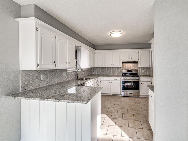 kitchen with sink, kitchen peninsula, light stone counters, stainless steel range oven, and white cabinetry