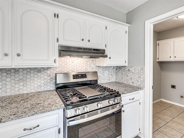 kitchen featuring light stone countertops, light tile patterned floors, stainless steel gas stove, and white cabinetry