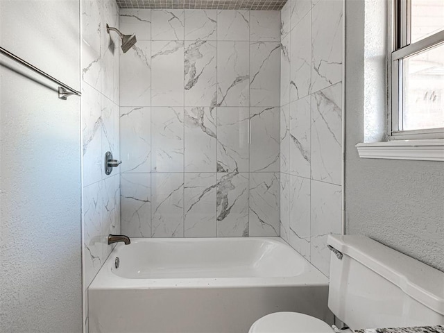 bathroom with tiled shower / bath combo and toilet