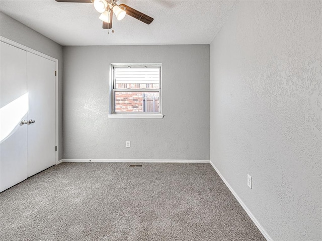 unfurnished bedroom with a textured ceiling, carpet floors, a closet, and ceiling fan