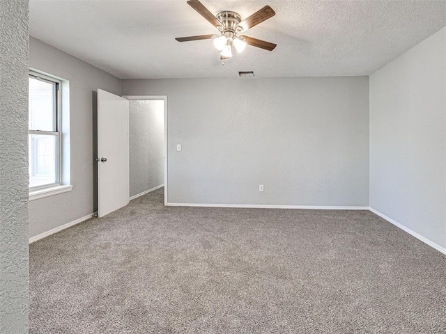 empty room featuring carpet flooring, ceiling fan, and a textured ceiling