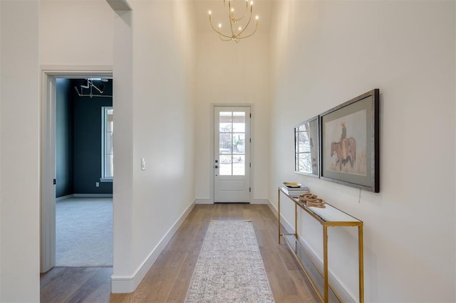 entryway with light hardwood / wood-style floors, a high ceiling, and a notable chandelier