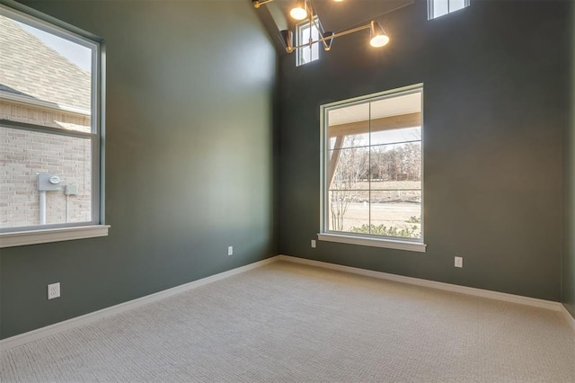 unfurnished room featuring carpet, a towering ceiling, and an inviting chandelier