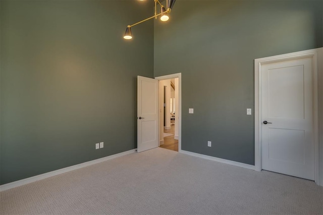 carpeted empty room featuring a high ceiling