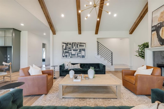 living room with a tiled fireplace, lofted ceiling with beams, light hardwood / wood-style floors, and an inviting chandelier