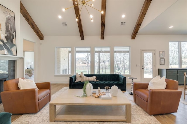 living room with lofted ceiling with beams, light hardwood / wood-style flooring, a notable chandelier, a healthy amount of sunlight, and a tiled fireplace