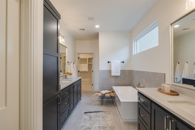 bathroom with tile patterned flooring, vanity, tile walls, and a tub