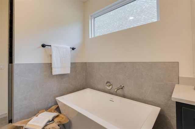 bathroom with a bathing tub, vanity, and tile walls