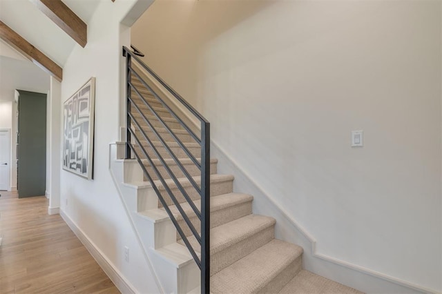 stairs with vaulted ceiling with beams and hardwood / wood-style flooring