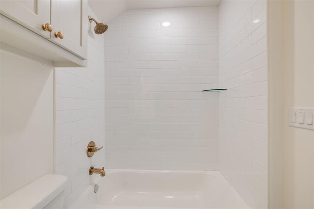 bathroom with toilet and tiled shower / bath