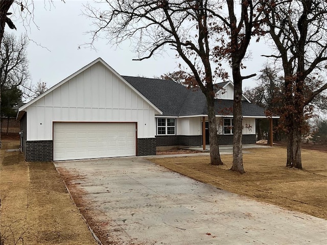 view of front facade with board and batten siding, an attached garage, brick siding, and driveway