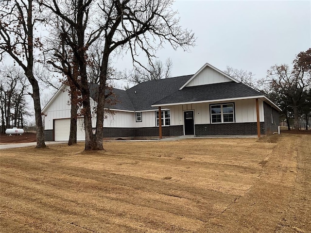 view of front of house featuring brick siding, an attached garage, a shingled roof, and board and batten siding