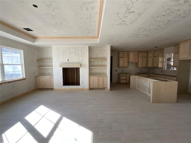 unfurnished living room with a high end fireplace, visible vents, a raised ceiling, and baseboards