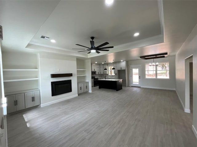 2402 Black Jack Way, Blanchard, OK 73010 - unfurnished living room featuring visible vents, ornamental molding, baseboards, recessed lighting, and a tray ceiling