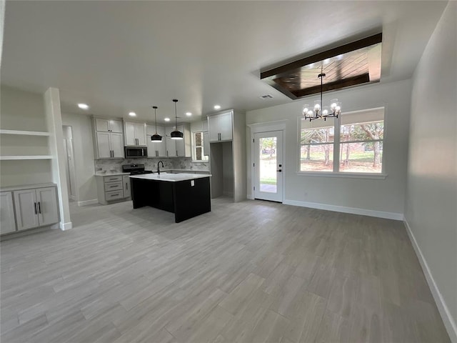 2402 Black Jack Way, Blanchard, OK 73010 - kitchen featuring appliances with stainless steel finishes, an inviting chandelier, a sink, a raised ceiling, and baseboards
