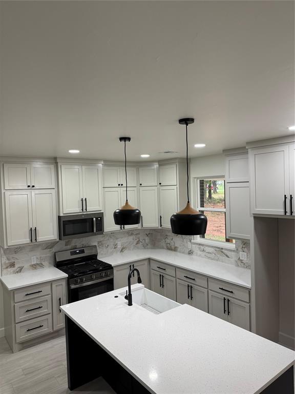2402 Black Jack Way, Blanchard, OK 73010 - kitchen with tasteful backsplash, a sink, light countertops, stainless steel appliances, and an island with sink
