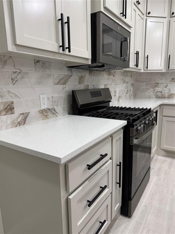 2402 Black Jack Way, Blanchard, OK 73010 - kitchen with light stone counters, white cabinets, backsplash, and gas stove