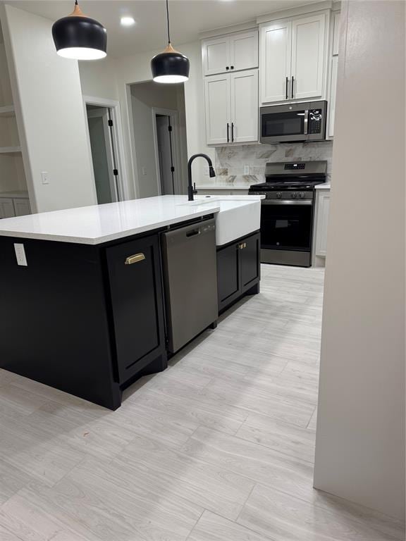2402 Black Jack Way, Blanchard, OK 73010 - kitchen with appliances with stainless steel finishes, tasteful backsplash, a center island with sink, light countertops, and a sink