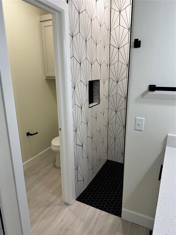 2402 Black Jack Way, Blanchard, OK 73010 - full bath with toilet, baseboards, a shower stall, and wood finished floors