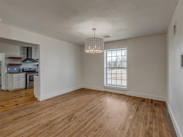 unfurnished dining area with a chandelier and light hardwood / wood-style flooring