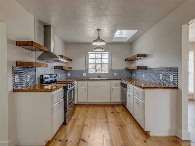 2832 NW 45th St, Oklahoma City, OK 73112 - kitchen with open shelves, stainless steel appliances, wall chimney exhaust hood, a skylight, and light wood-style floors