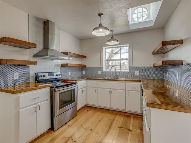 kitchen with stainless steel electric stove, decorative light fixtures, white cabinetry, and wall chimney range hood