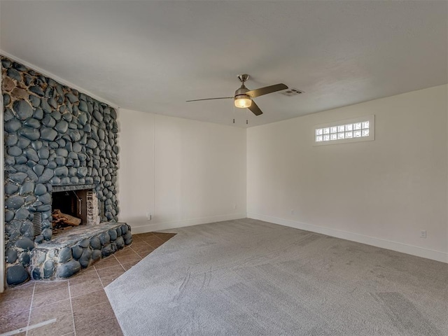 unfurnished living room featuring a stone fireplace, ceiling fan, and light colored carpet