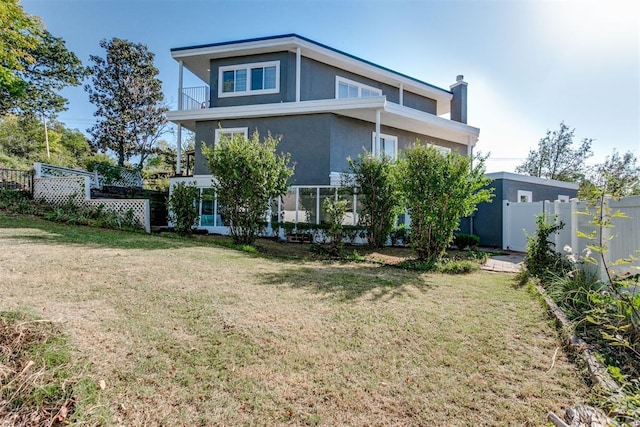 rear view of house with a balcony and a yard