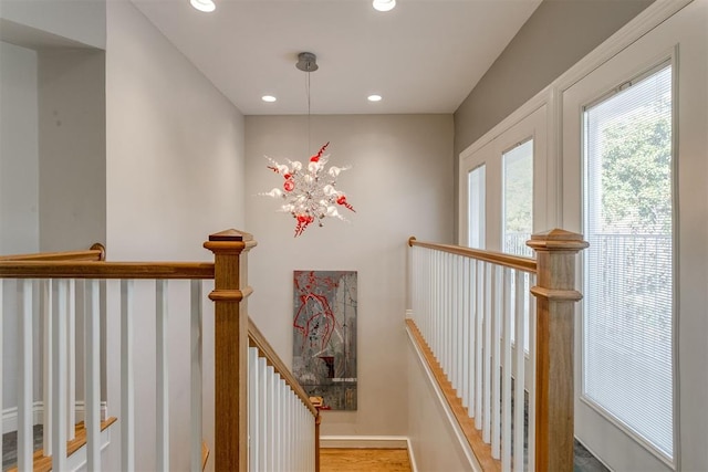 stairway featuring hardwood / wood-style flooring and an inviting chandelier