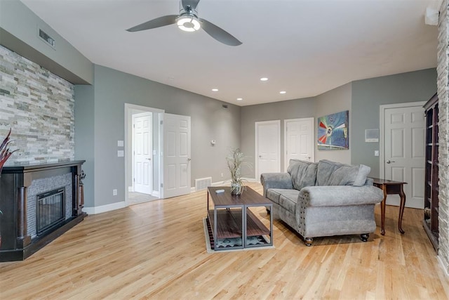 living room with a fireplace, light hardwood / wood-style flooring, and ceiling fan