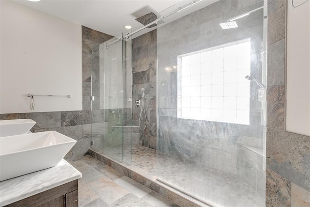 bathroom featuring a tile shower, tile walls, and sink