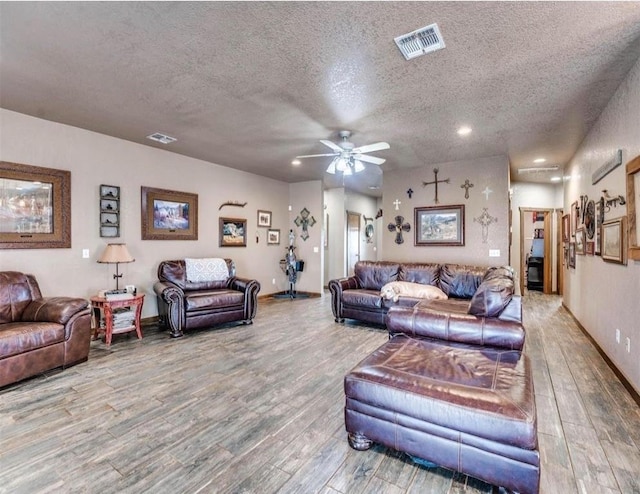 living room with a textured ceiling, hardwood / wood-style flooring, and ceiling fan