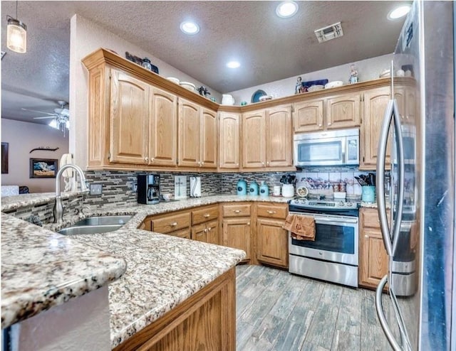 kitchen with sink, hanging light fixtures, stainless steel appliances, kitchen peninsula, and a textured ceiling