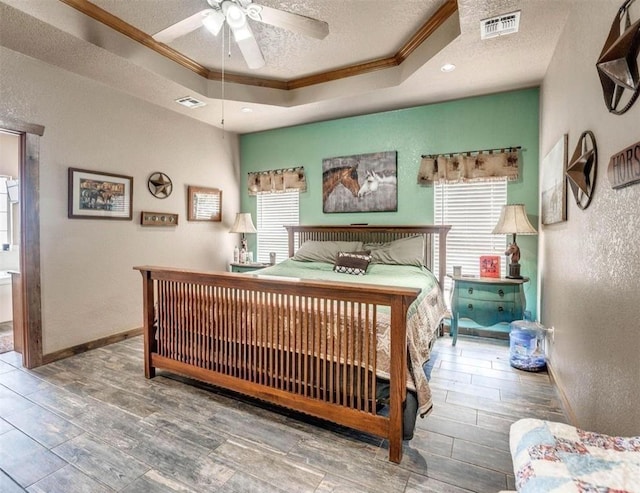 bedroom with a raised ceiling, crown molding, ceiling fan, and a textured ceiling