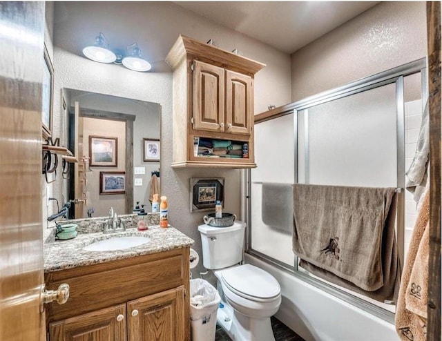 full bathroom with vanity, bath / shower combo with glass door, and toilet