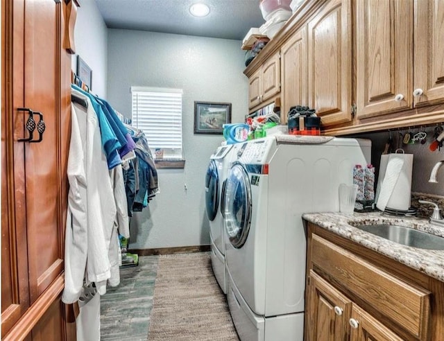 clothes washing area featuring cabinets, sink, light hardwood / wood-style flooring, and washing machine and clothes dryer