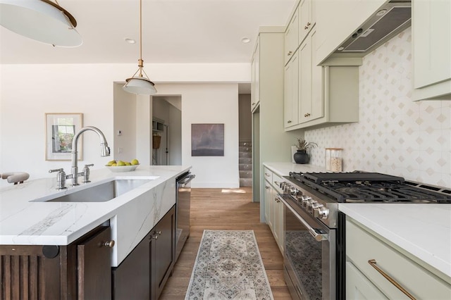 kitchen featuring light stone counters, hanging light fixtures, cream cabinets, and stainless steel appliances