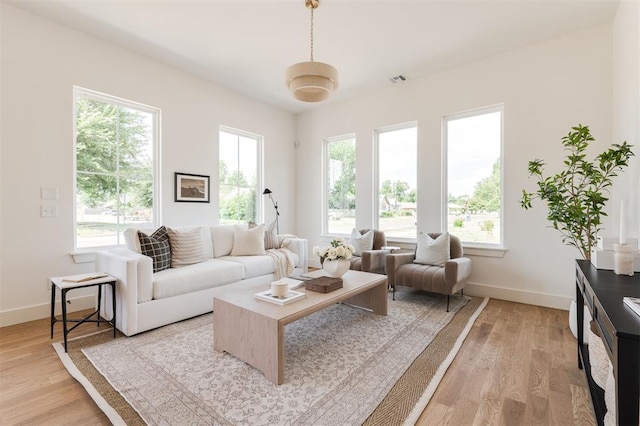 living room featuring plenty of natural light, baseboards, and light wood finished floors