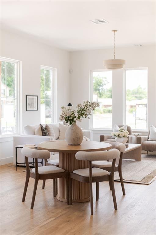 dining room with breakfast area, visible vents, a healthy amount of sunlight, and light wood finished floors