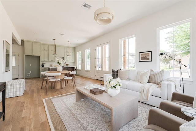 living area featuring light wood-type flooring and visible vents