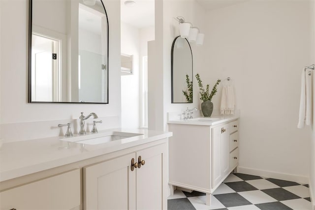 full bathroom featuring tile patterned floors, two vanities, baseboards, and a sink