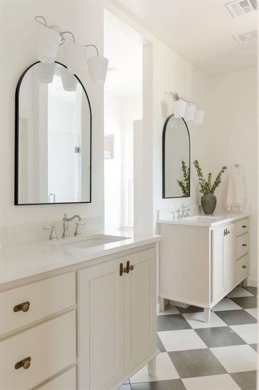 bathroom featuring tile patterned floors, visible vents, two vanities, and a sink