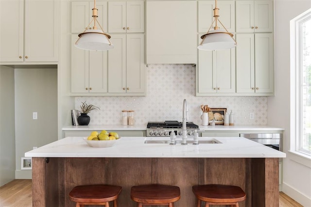 kitchen featuring tasteful backsplash, light stone countertops, a breakfast bar, and a kitchen island with sink