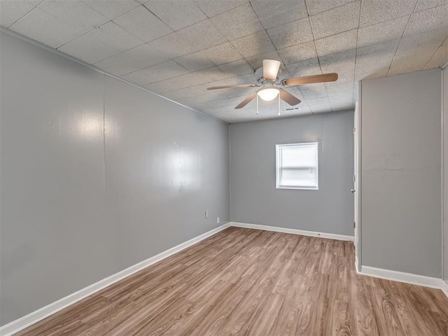 empty room with ceiling fan and light hardwood / wood-style flooring