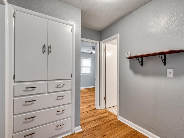 hall featuring light hardwood / wood-style floors and a textured ceiling