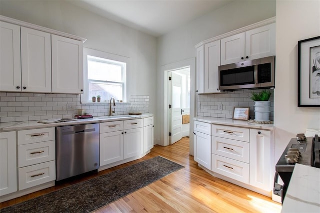 kitchen with white cabinets, light wood-type flooring, stainless steel appliances, and sink