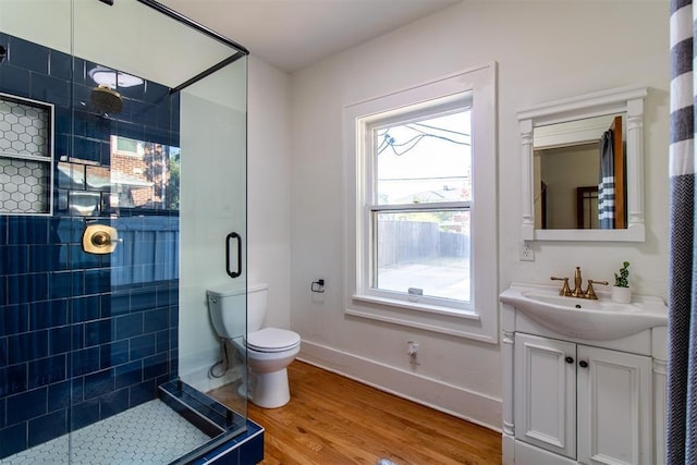 bathroom with tiled shower, hardwood / wood-style flooring, vanity, and toilet