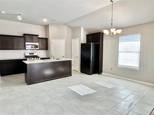 kitchen featuring stainless steel appliances, an inviting chandelier, backsplash, dark brown cabinets, and a center island with sink