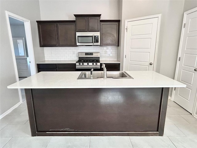 kitchen with a center island with sink, sink, dark brown cabinetry, and stainless steel appliances